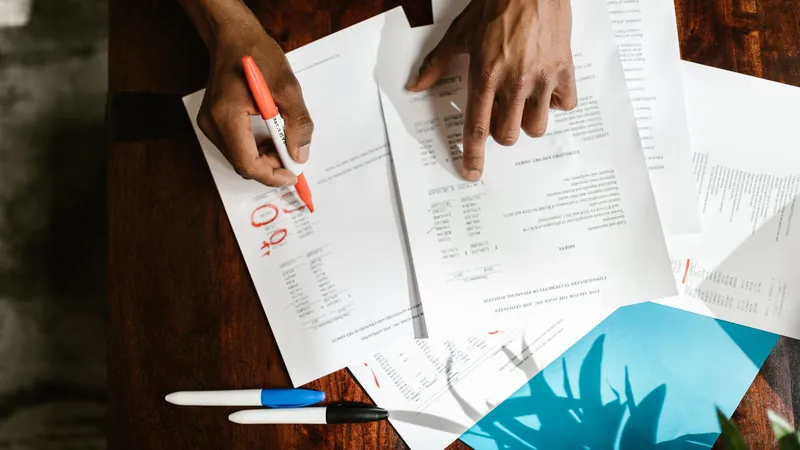 Hands marking up insurance and billing documents on a desk