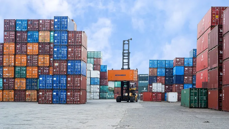 Stacked shipping containers in a freight yard under a blue sky