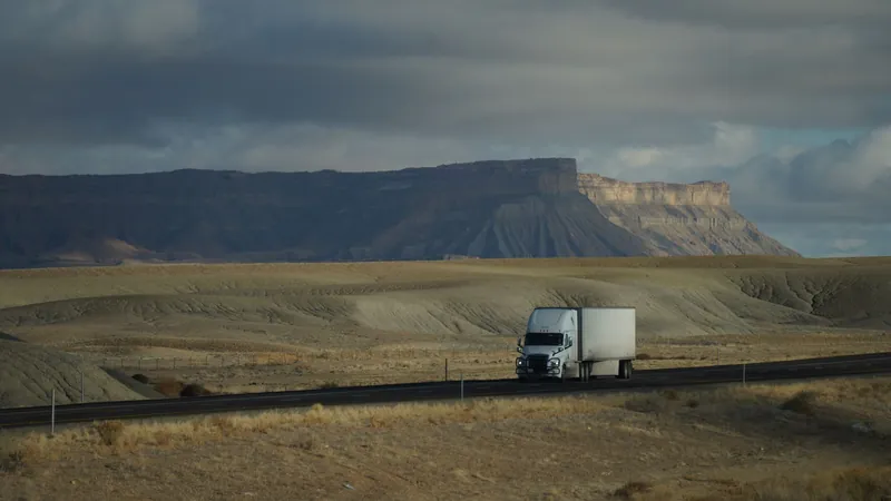 Semi truck crossing a wide desert highway under dramatic clouds